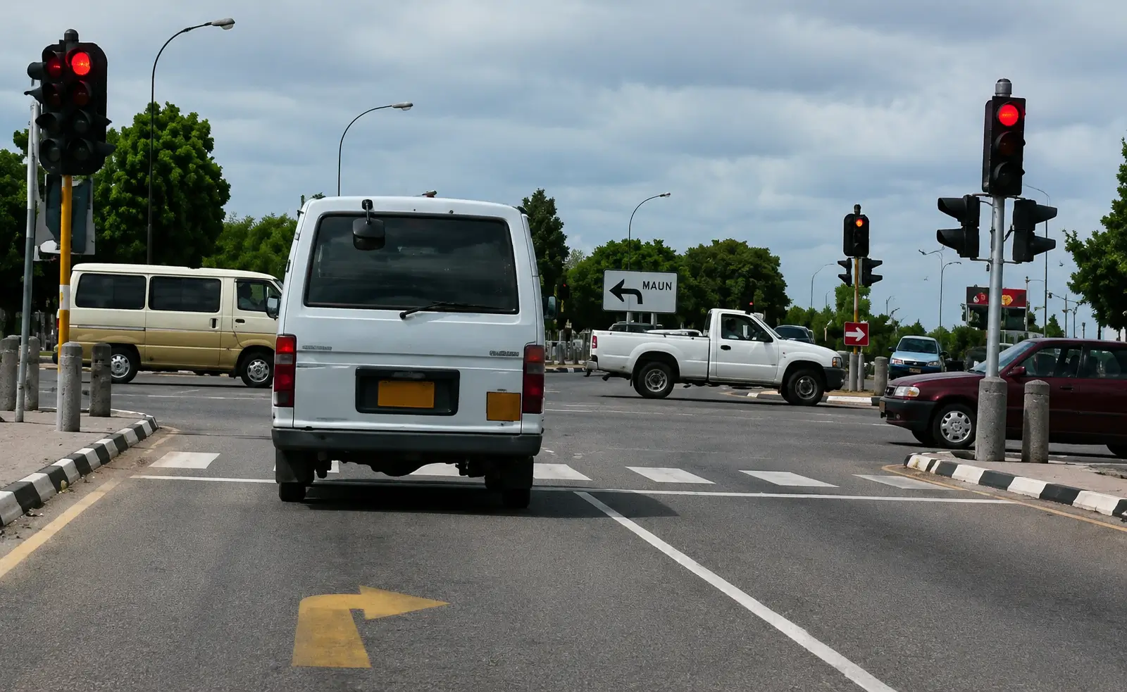 Driver's view at a junction with traffic lights showing red, a van ahead